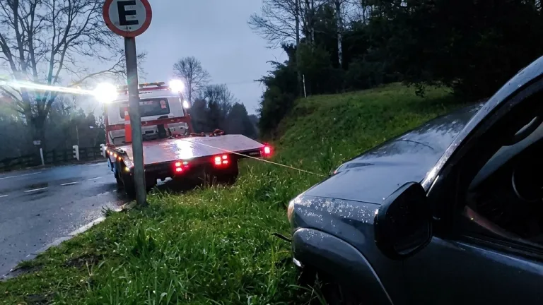 Grúa rescatando con cable una camioneta que se salió del camino entre Villarrica y Pucón.